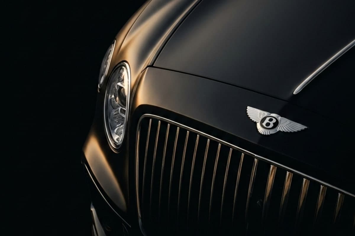 Detalle frontal de un Bentley negro sobre fondo oscuro, faro y parrilla cromada iluminados por luz lateral cálida